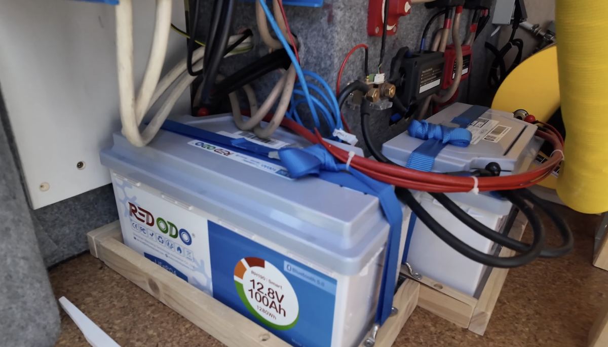 Sichere LiFePO4 Batteriehalterung im Camper mit Holzrahmen und Spanngurt