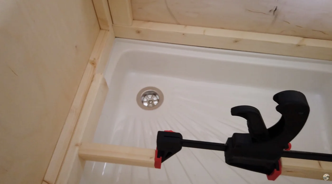 Holzrahmen und Schraubzwinge an der Duschwanne im Camper-Ausbau