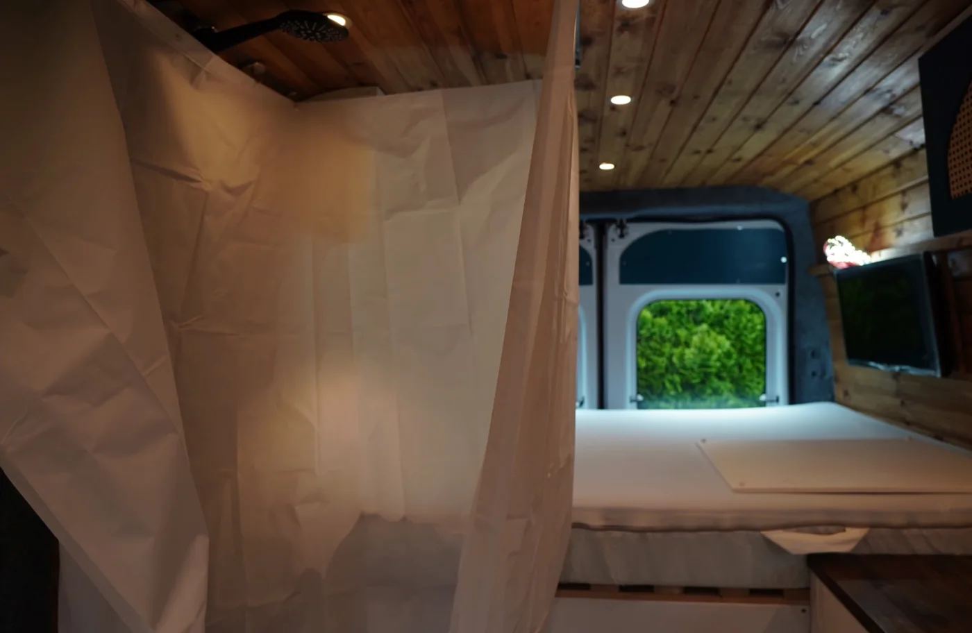 Aufgebauter Duschvorhang der versteckten Camper-Dusche neben dem Bett